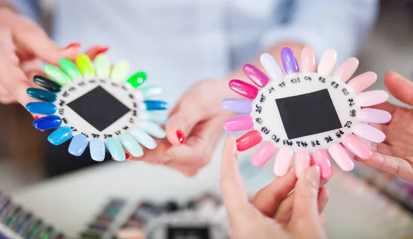 Две женщины выбирают красочные искусственные ногти в салоне красоты — стоковое фото