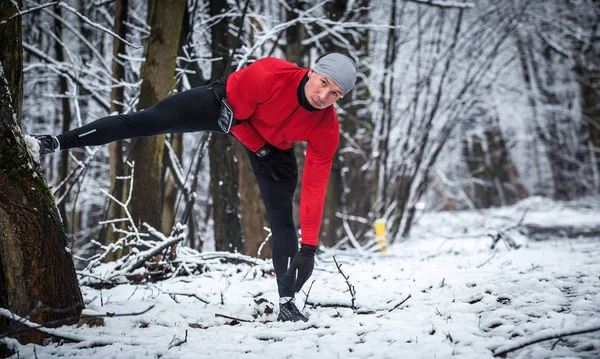 Зимние беговые тренировки, бег на растяжку в холодном снежном парке — стоковое фото