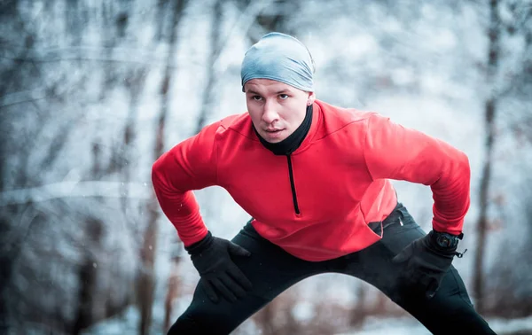 Winter running exercise, runner stretching on road in snowy fore