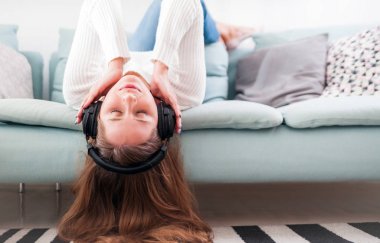 Rahat kadın evde kanepe üzerinde kulaklık ile müzik dinleme