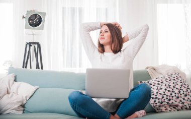 Kadın evde kanepede oturan ve dizüstü bilgisayarınızla çalışırken germe