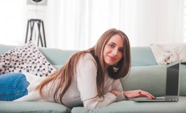 Kendine güvenen kadın evde koltukta yalan ve laptop ile çalışma