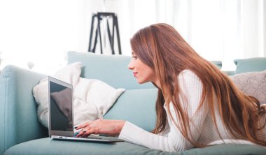Kendine güvenen kadın evde koltukta yalan ve laptop ile çalışma