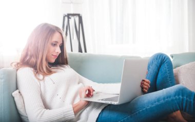 Kendine güvenen kadın evde koltukta yalan ve laptop ile çalışma
