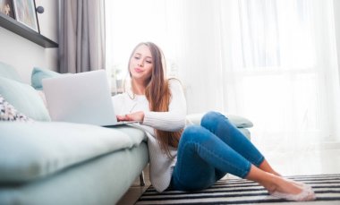 Kadın evde kanepe ve dinlenme dizüstü bilgisayar kullanarak