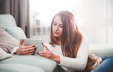 Kadın evde katta oturan ve tablet bilgisayar kullanarak