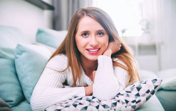 Smiling young woman relaxing on sofa at home — Stock Photo, Image