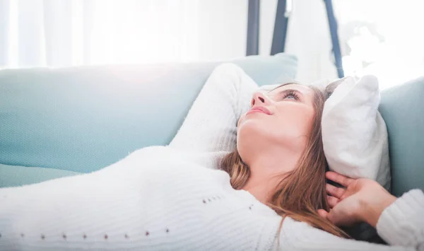 Smiling young woman at home lying on sofa — Stock Photo, Image