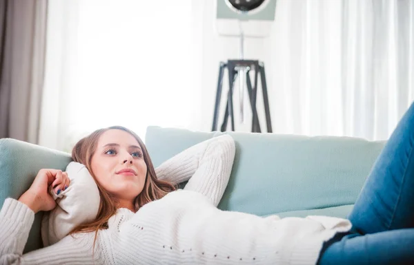 Mosolygó fiatal nő otthon feküdt a kanapén — Stock Fotó