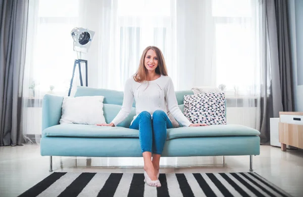 Pretty woman at home sitting on sofa in modern interior — Stock Photo, Image