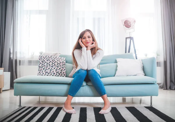Pretty woman at home sitting on sofa in modern interior — Stock Photo, Image