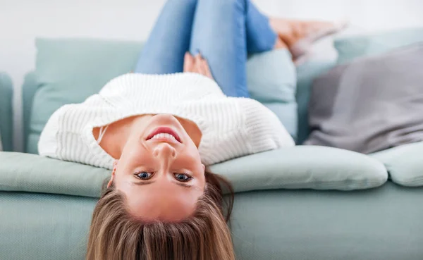 Счастливая женщина расслабляется и ложится на диван дома — стоковое фото