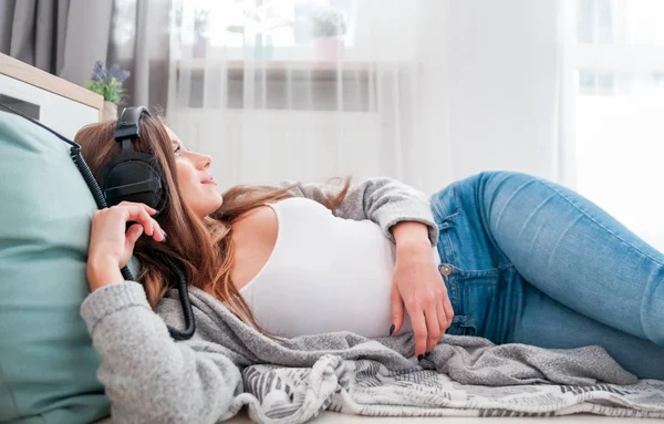 Mladá žena se sluchátky, ležící na podlaze, poslech hudby při — Stock fotografie