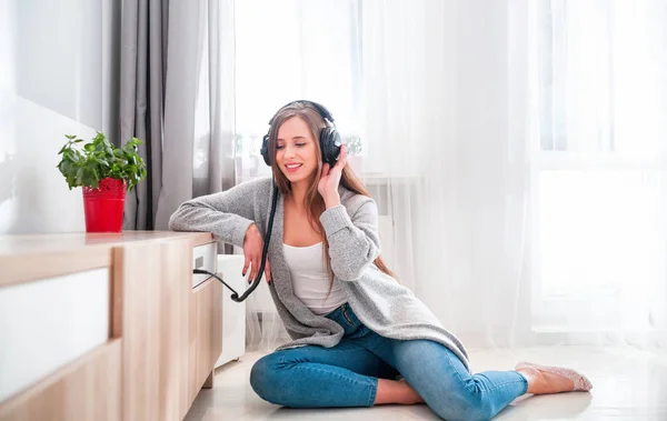 Frau mit Kopfhörer hört zu Hause im Wohnzimmer Musik — Stockfoto