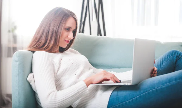 Självsäkra kvinnan hemma liggande på soffan och arbetar med laptop — Stockfoto