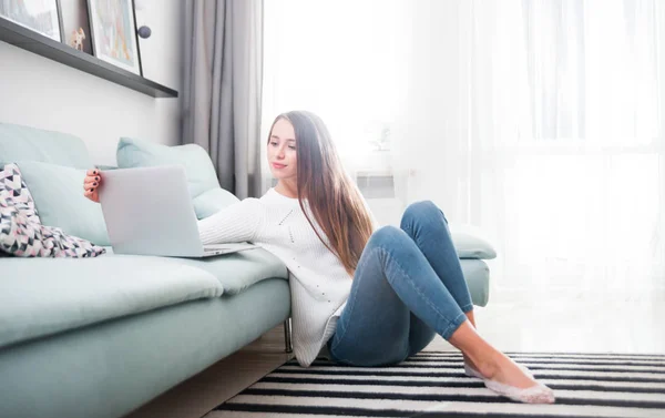 Жінка вдома використовує ноутбук на дивані і відпочиває — стокове фото