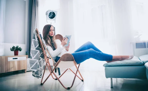 Junge Frau Sitzt Hause Auf Modernem Stuhl Und Benutzt Tablet — Stockfoto