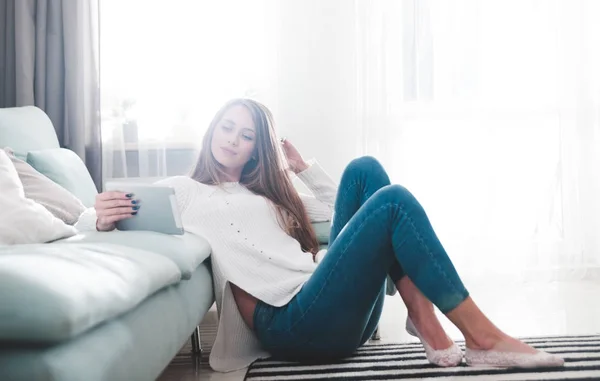 Жінка вдома сидить на килимі і використовує планшетний комп'ютер — стокове фото
