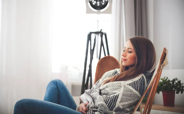 Frau sitzt zu Hause auf modernem Stuhl am Fenster und entspannt sich im Wohnzimmer — Stockfoto