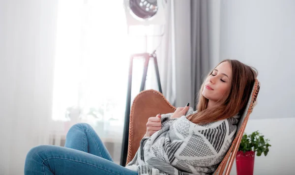 Frau sitzt zu Hause auf modernem Stuhl am Fenster und entspannt sich im Wohnzimmer — Stockfoto