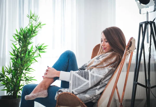 Vrouw thuis zit op moderne stoel in de buurt van venster ontspannen in woonkamer — Stockfoto