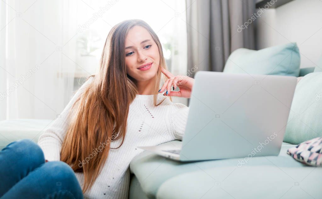 Woman at home using laptop computer on sofa and resting