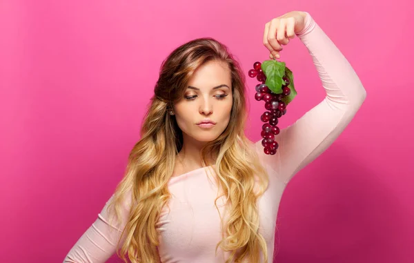 Žena s hroznovým vínem na růžovém pozadí — Stock fotografie