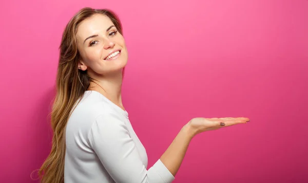 Vrouw op roze achtergrond weergeven iets en ruimte bieden, kopiëren — Stockfoto