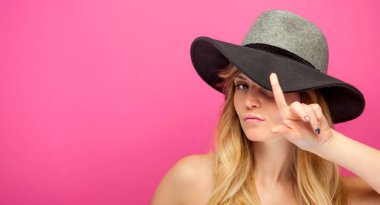 Şapka ve pembe bir arka plan üzerinde uzun sarı saçlı güzel genç kadın