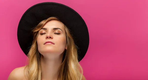 Beautiful young woman with hat and long blonde hair on pink background — Stock Photo, Image