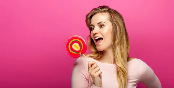 Vacker ung kvinna med stora lollipop på rosa bakgrund, kopiera utrymme — Stockfoto