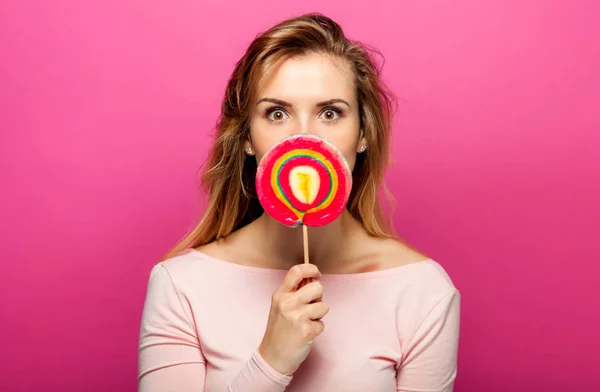 Bella giovane donna con grande lecca-lecca su sfondo rosa — Foto Stock