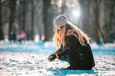 Genç kadın kartopu güneşli gün kış parkta yapma.