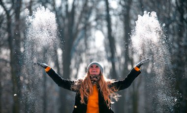 Gülümseyen genç kadın güneşli kış günü kar hava atma