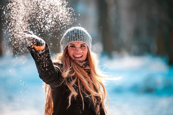 笑みを浮かべてカメラを見て空気で雪を投げる女性 — ストック写真