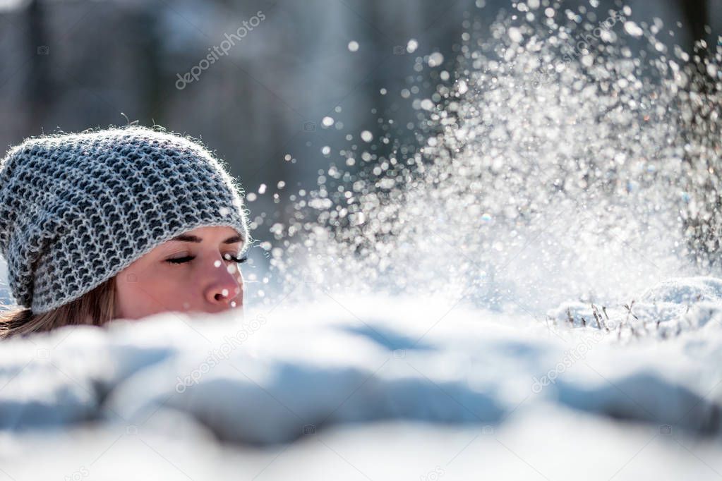 Young woman blowing snow in winter park