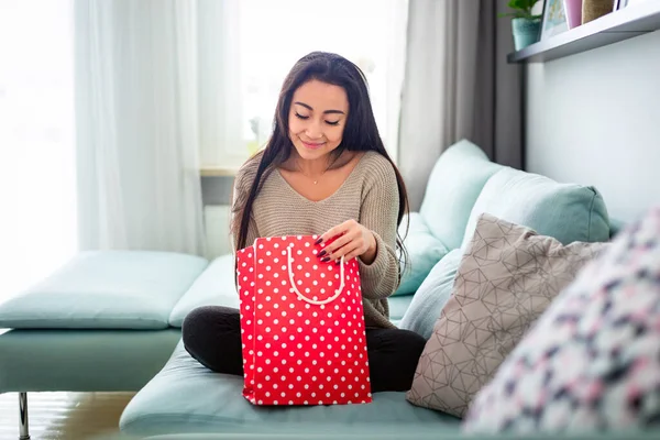 Mujer asiática en casa mirando bolsa de regalo roja —  Fotos de Stock