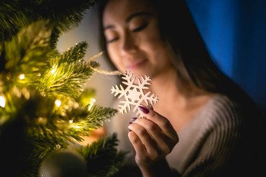 Akşam evde Noel ağacı süsleyen güzel Asyalı kadın.