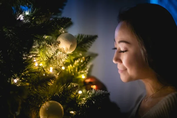 Mooie Aziatische vrouw versieren kerstboom in huis 's avonds — Stockfoto
