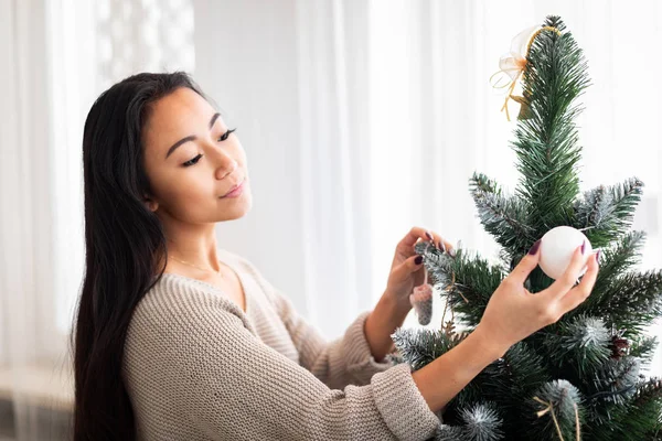 Jonge Aziatische vrouw versieren kerstboom thuis — Stockfoto