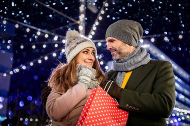 Çift geceyi ışık süslemeleriyle dolu bir Noel pazarında geçiriyor.