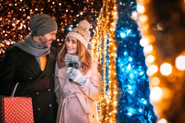 Sokakta Noel süslemeleri arasında yürürken sevgi dolu bir çift