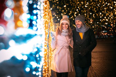 Mutlu çift Noel için süslenmiş bir sokakta yürüyor.