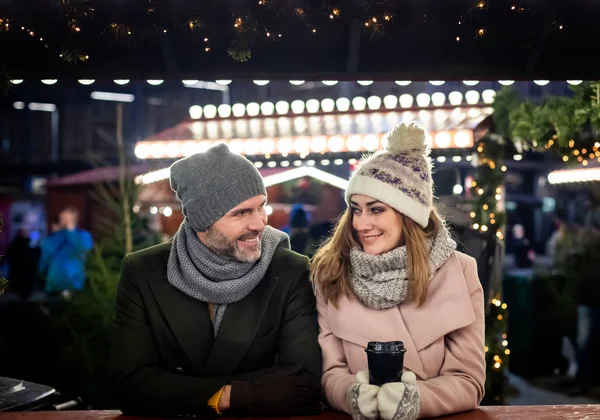 愛するカップルは、夜の間に装飾されたクリスマスマーケットを訪れます — ストック写真