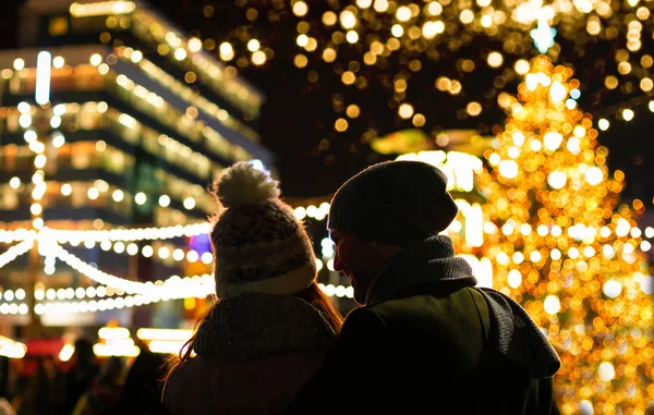 Пара вечером смотрит на украшенный рождественский базар — стоковое фото