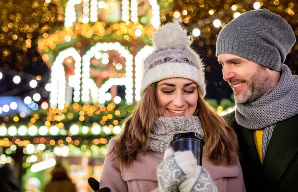 Milující pár na pozadí zimní prázdniny dekorace během večerní procházky kolem vánočního veletrhu — Stock fotografie