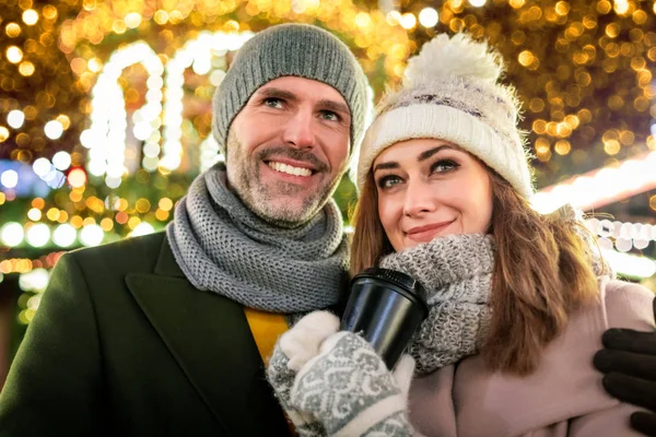 Casal amoroso no fundo de férias de inverno decorações durante uma caminhada à noite em torno da feira de Natal — Fotografia de Stock