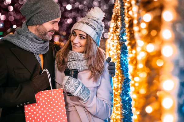 Glückliches Paar spaziert auf einer weihnachtlich geschmückten Straße — Stockfoto