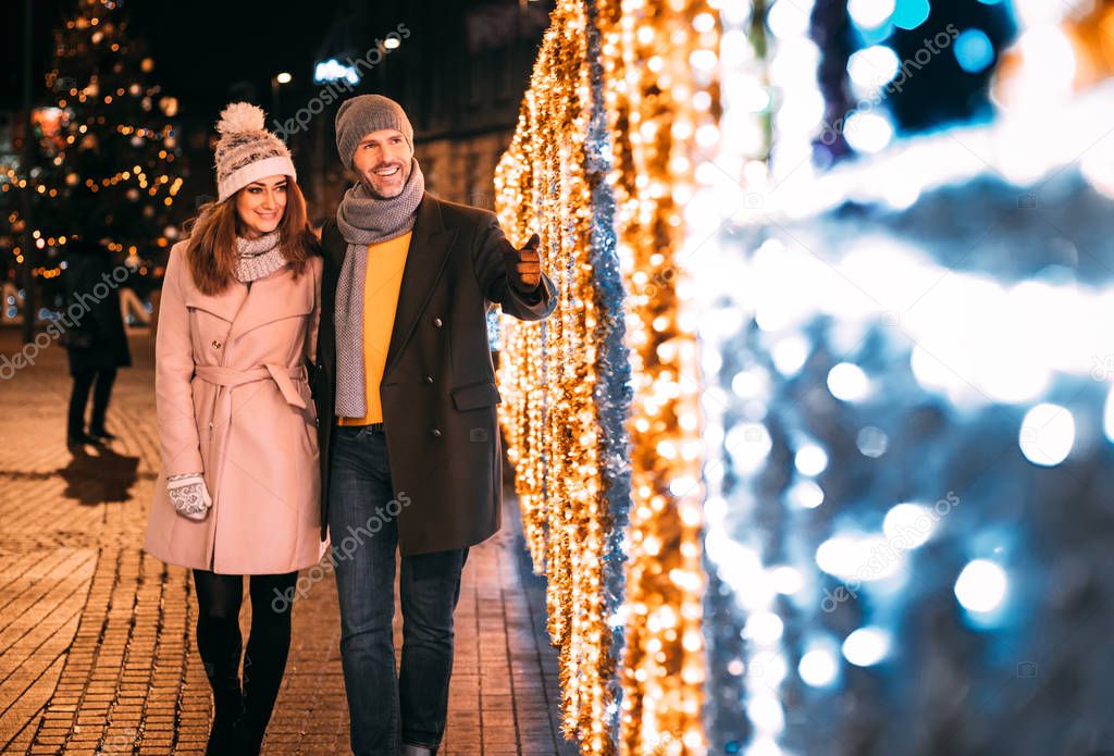 Loving couple while walking between Christmas decorations on the street