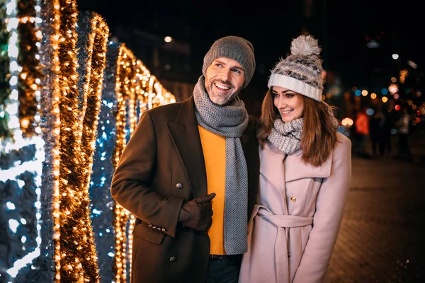 幸せなカップルはクリスマスのために飾られた通りを歩く — ストック写真